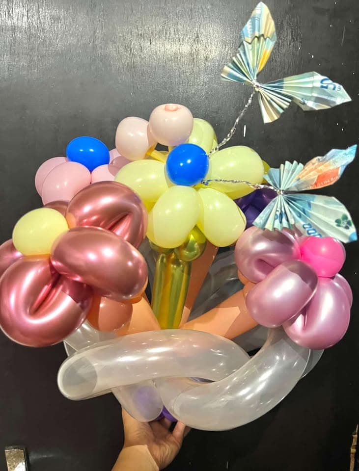 Buket balon boneka teddy bear cokelat menggemaskan di tengah hamparan balon bunga pastel