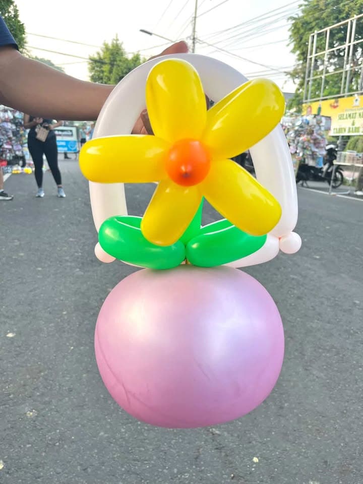 Bunga balon kuning dan oranye pada vas bulat merah muda
